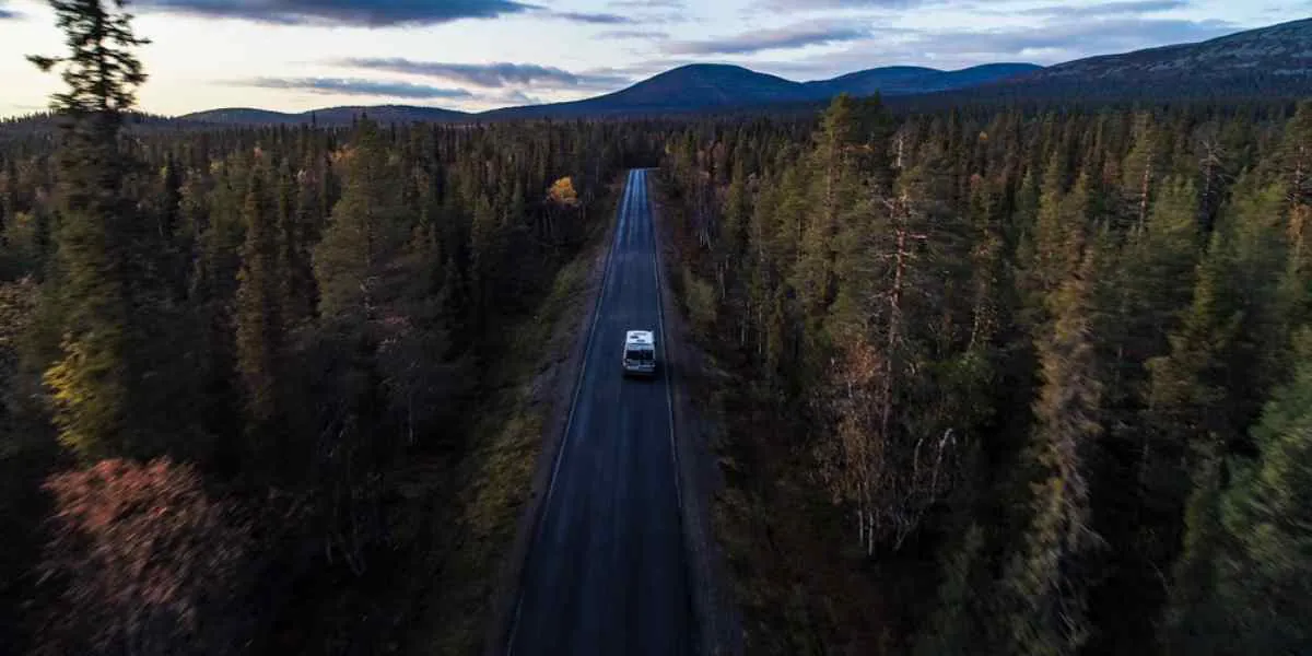 Camper en una carretera entre bosques en Suecia