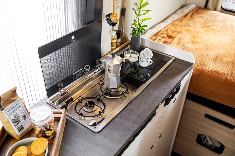 Cocina con fogones de gas y fregadero dentro de una camper