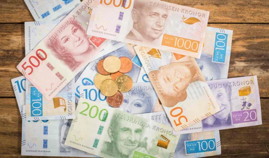 Billetes y monedas de coronas suecas sobre una mesa de madera