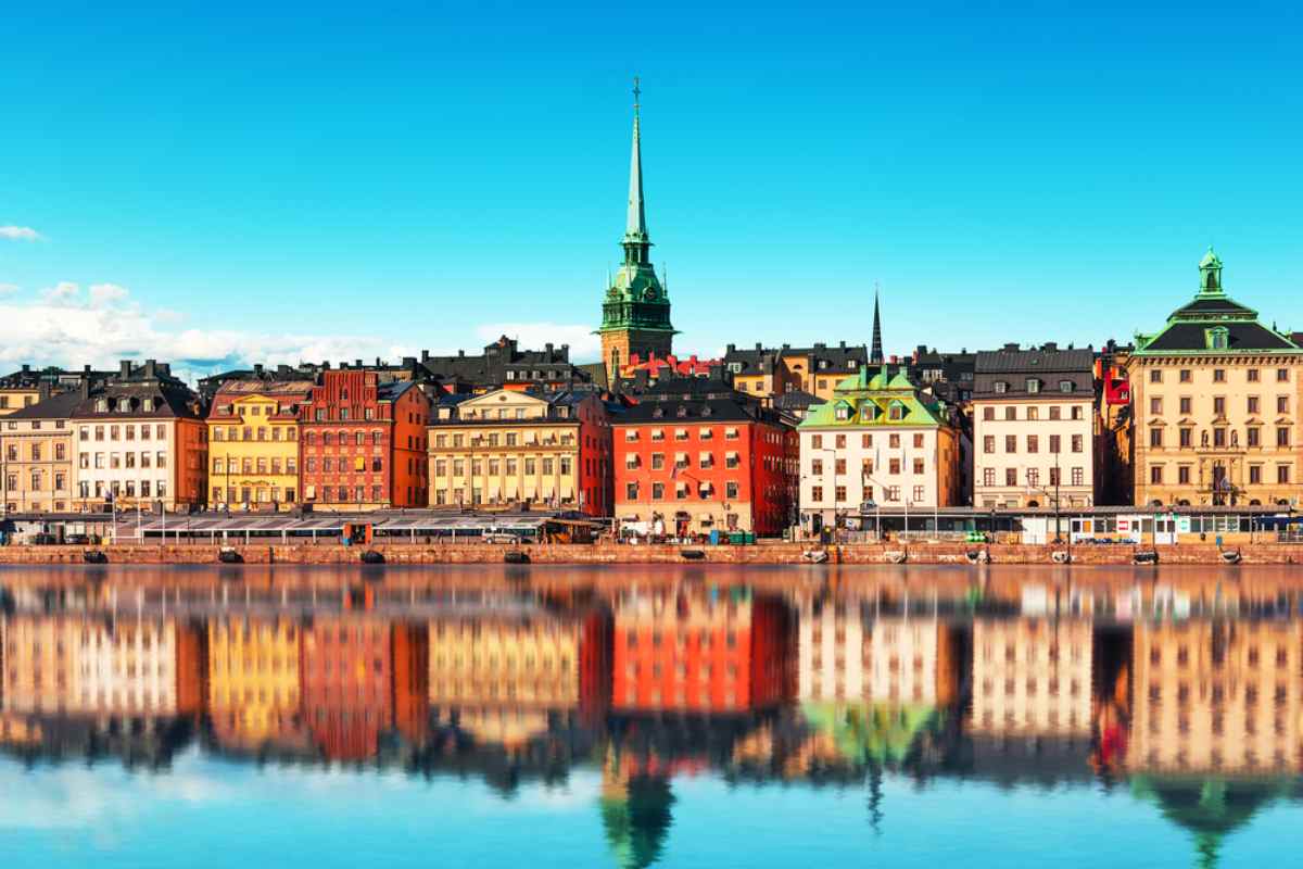 Gamla stans färgrika fasader med speglingar i vattnet – klassiskt stadsstopp i Stockholm på en roadtrip i Sverige.