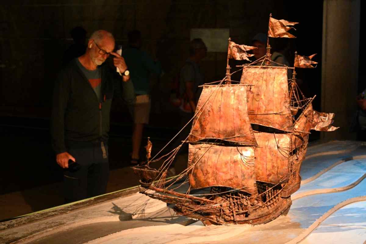 Ein Mann betrachtet ein Segelboot in einer Museumsausstellung in Stockholm genau.