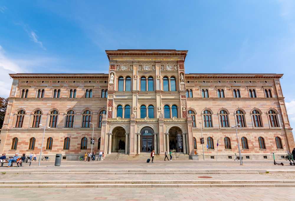 General view of the façade of the Nationalmuseum in Stockholm, with a reddish color that simulates exposed brick and curious semicircular arches at the entrance and windows.