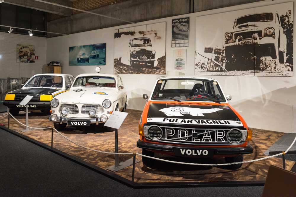 Detailed view of one of the areas of the Volvo Museum in Gothenburg with several vintage cars on display in front of a mural with photographs.