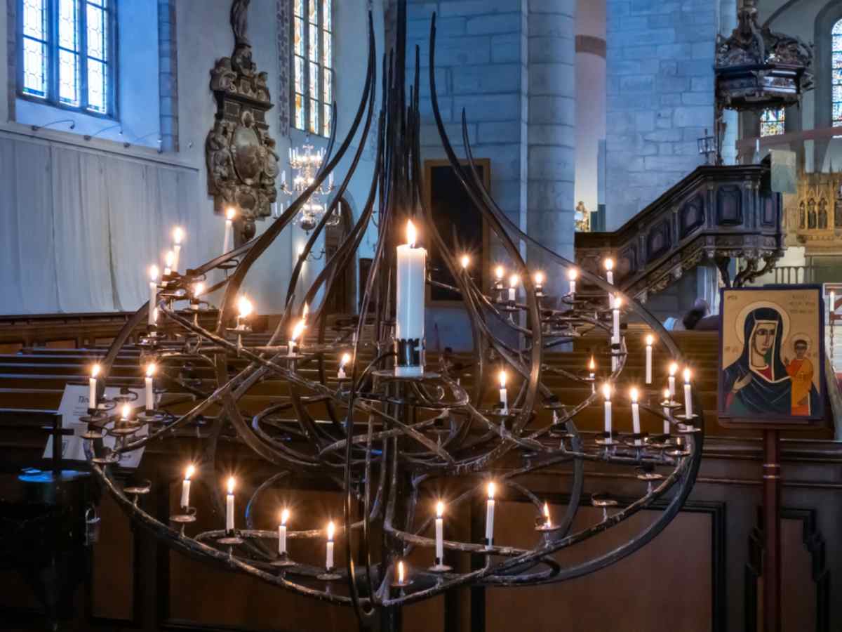 Innenraum des Doms von Visby auf Gotland, Schweden, mit einem einzigartigen Kronleuchter mit brennenden Kerzen und religiösen Ikonen.