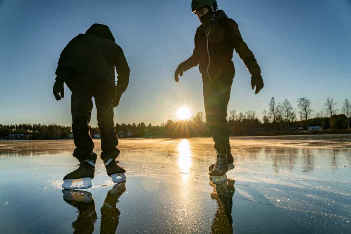 Två personer åker skridskor på en frusen sjö nära Umeå, Sverige.
