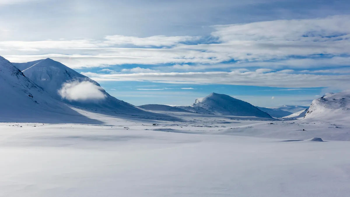 Rolig soluppgång över en lugn sjö längs Kungsledens vandringsled i Swedish Lapland