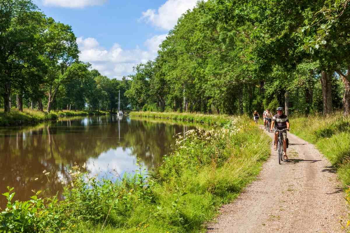 Cyklande njuter av sin rutt nära Sveriges Göta kanal på en vacker solig dag.