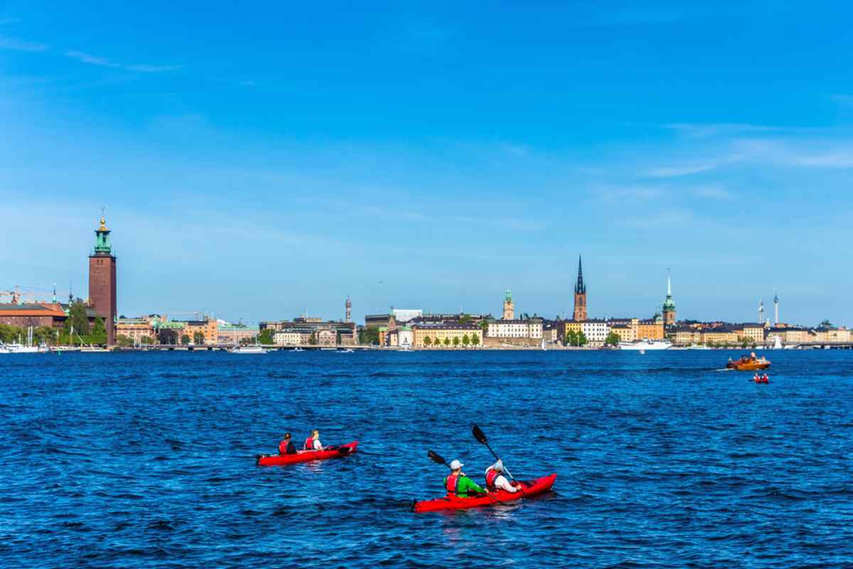 Flera personer paddlar kajak i Stockholms skärgård med lätt vågig sjö.