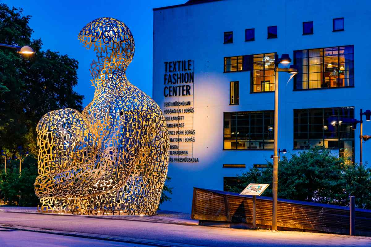 Skulptur av en människokropp formad som bokstäver utanför Textile Fashion Center i Borås under blå timmen.