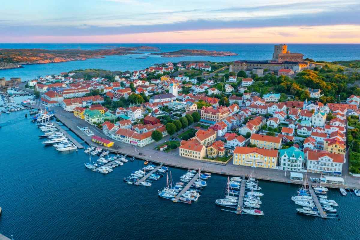 Marina filled with boats, colorful houses, and Carlstens Fortress at sunset on Sweden’s west coast.