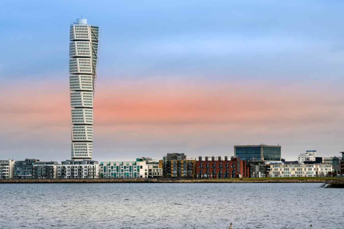 Malmö waterfront skyline with the Turning Torso twisting skyscraper rising above modern apartments at dusk.