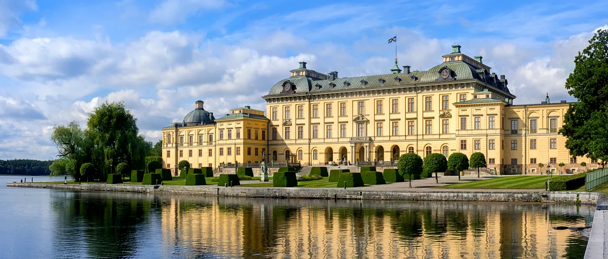 Scenic view of Drottningholm Palace in Sweden, with its grand architecture reflected in the tranquil waters.