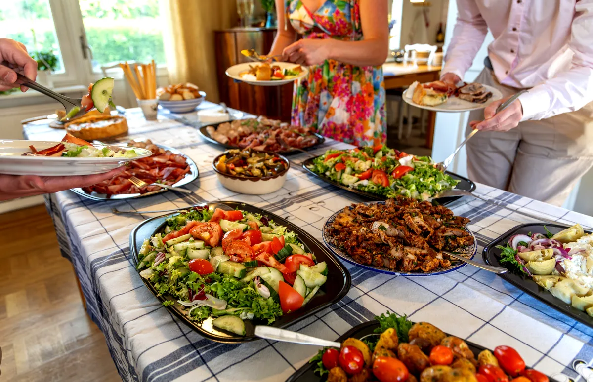 A vibrant Swedish smorgasbord with various salads, meats, and other dishes served on a table, with people filling their plates