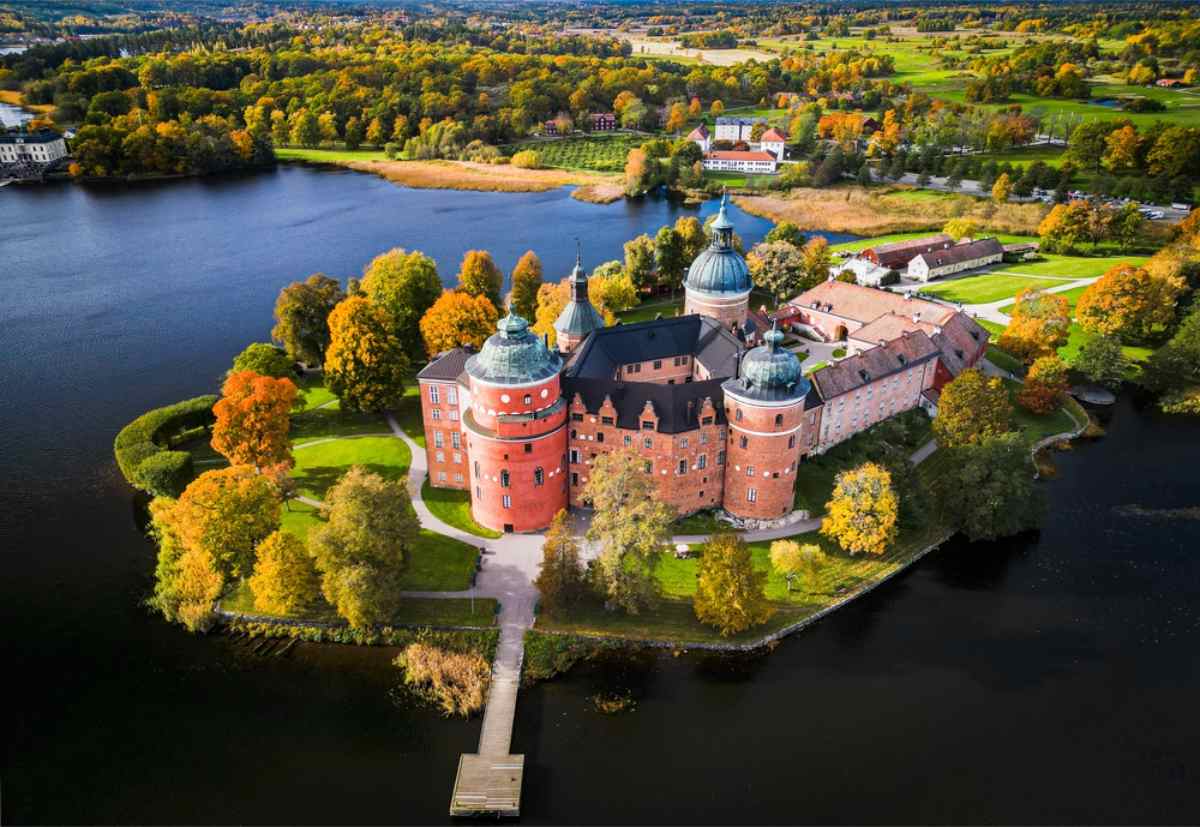 Drohnenaufnahme von Schloss Gripsholm in Schweden mit seiner rosa Farbe, der runden Fassade und dem schönen umliegenden See.