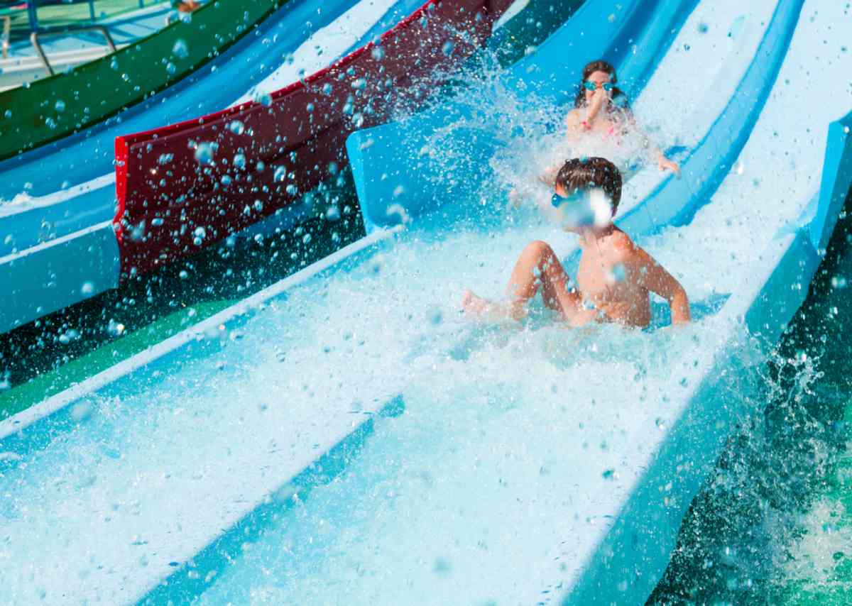 Kinder spielen auf bunten Wasserrutschen auf einem Campingplatz mit Wasserpark in der Nähe von Stockholm.