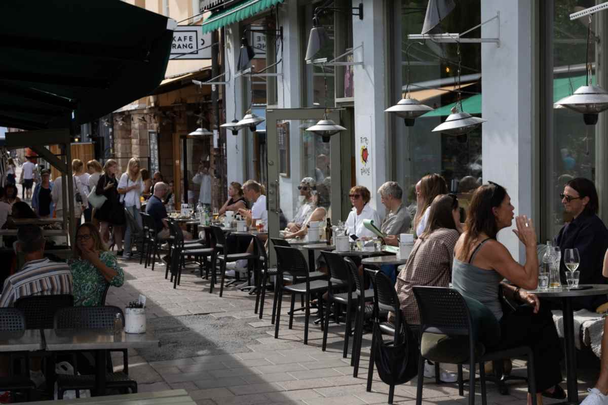 Allgemeiner Blick auf eine belebte Straße im schwedischen Stadtteil Södermalm, wo viele Menschen auf den Terrassen von Restaurants zu Mittag essen.