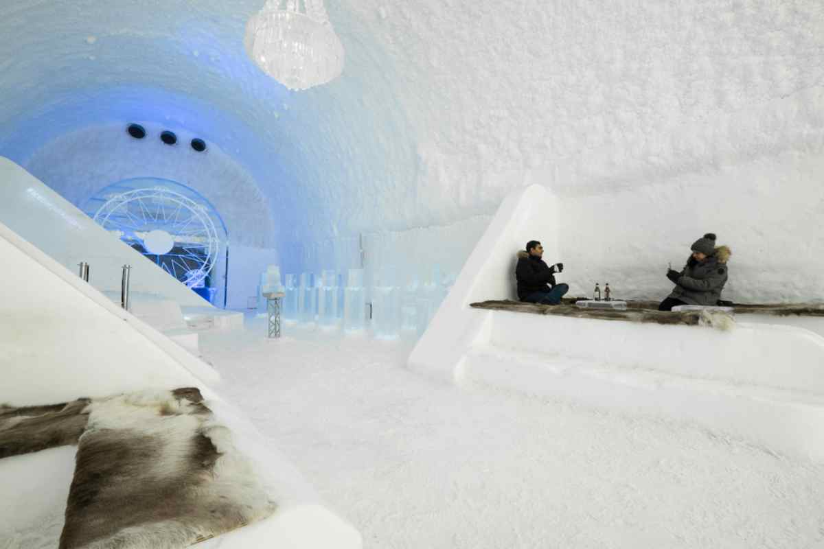 Ein Paar Touristen, in warmer Kleidung, sitzt auf einem Eisblock im berühmten Icehotel in Schweden.