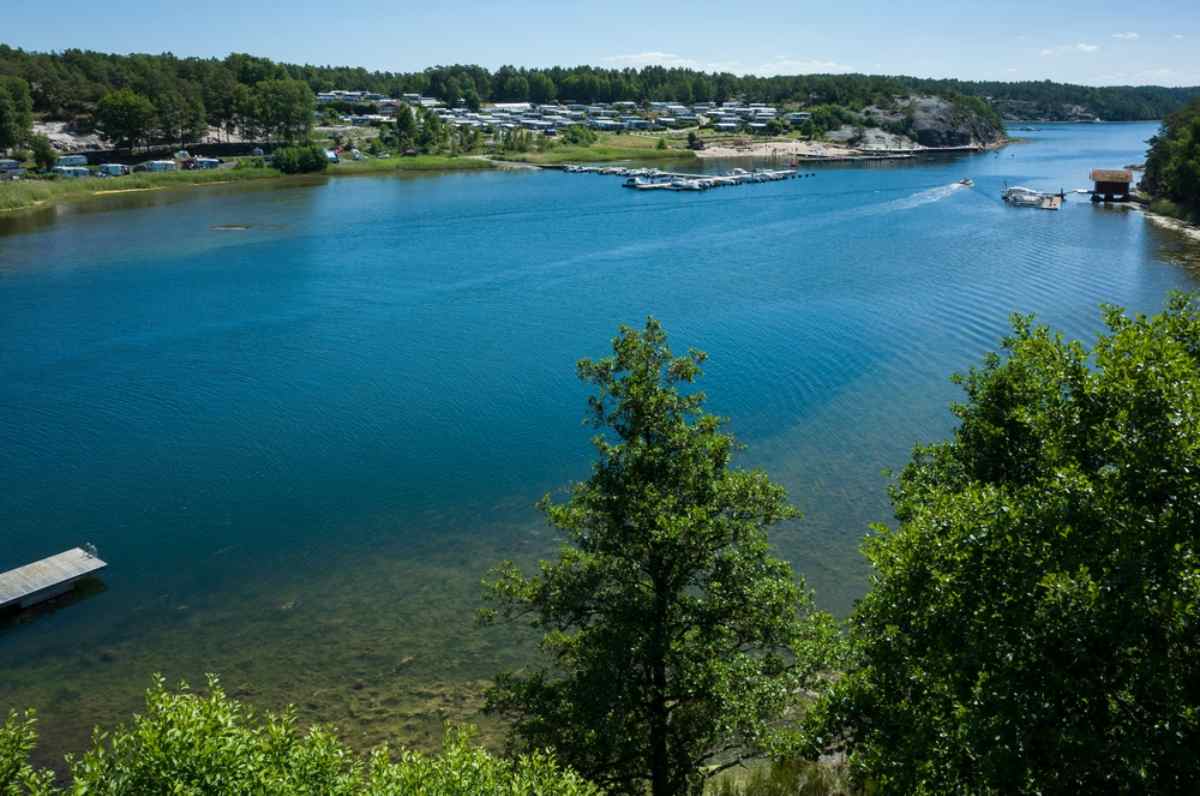 General view of a lake with calm turquoise waters and a lot of human activity on the other side of the lake.