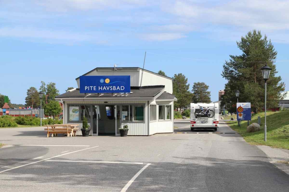 General view of the gatehouse at the Pite Havsbad campground in Sweden with a motorhome with bikes in the back through the entrance gate.