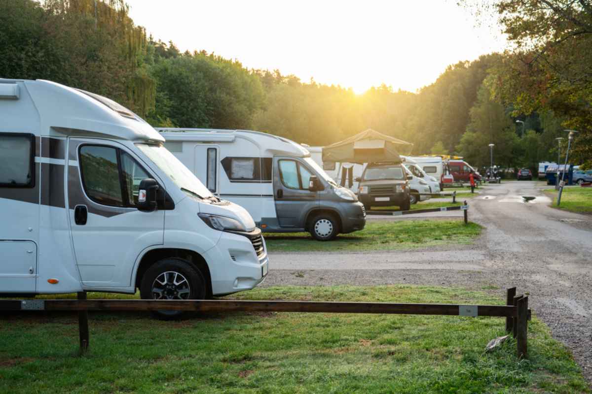 Row of white motorhomes on a green campsite near Stockholm at sunrise, a perfect base for day trips and summer road adventures in Sweden.