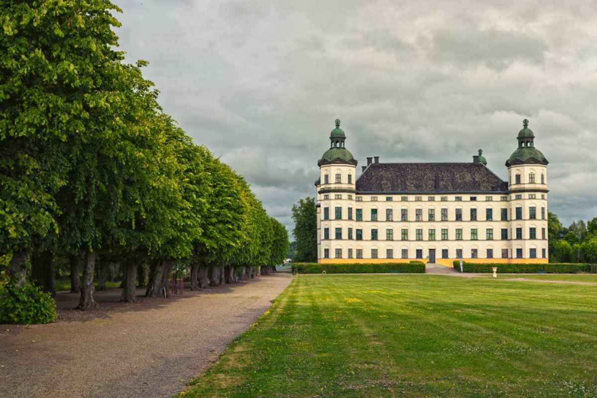 Skokloster Castle framed by formal lawns and tree-lined paths under gray skies, an easy historical day trip northwest of Stockholm.