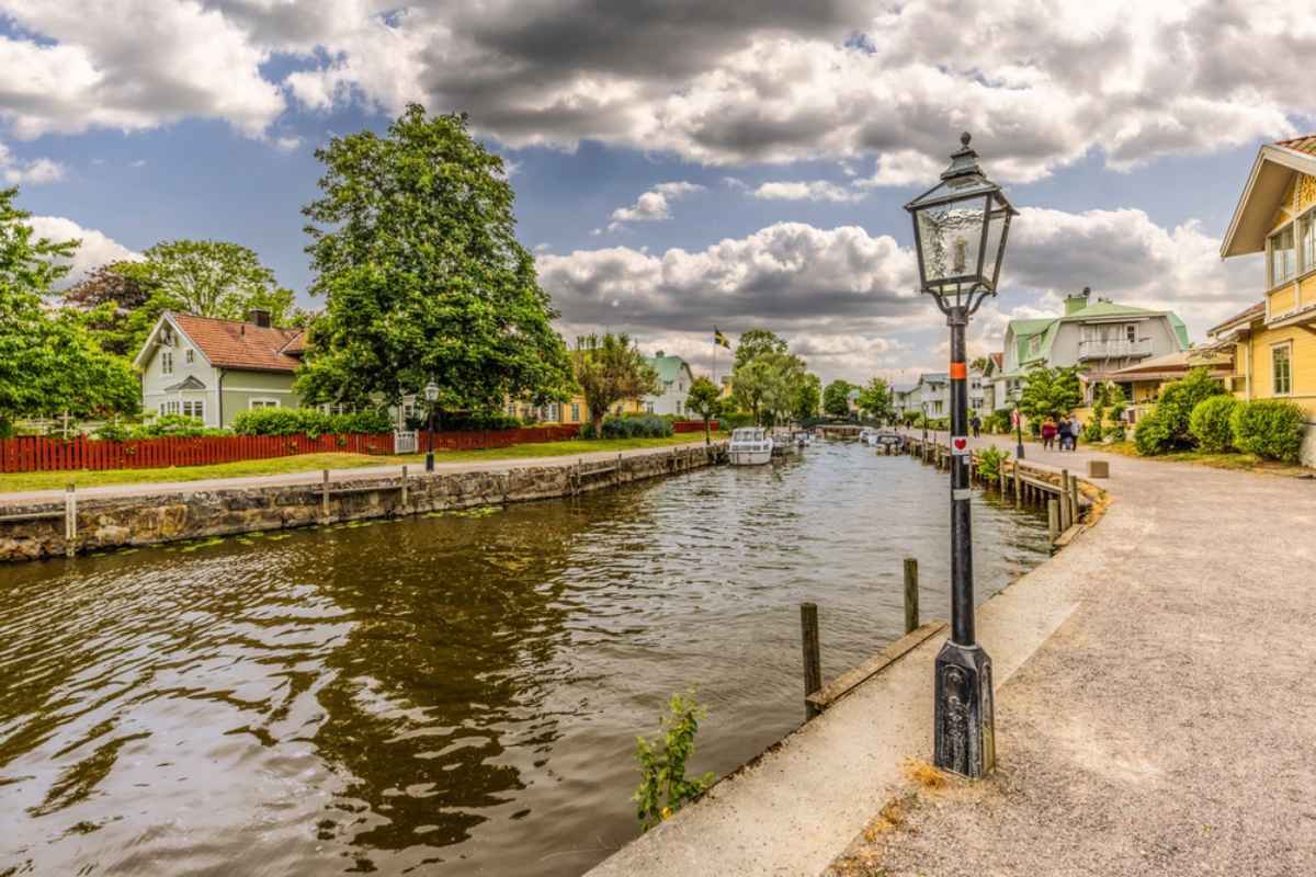 Colorful wooden houses and boats along a calm canal in Trosa, Sweden, a charming small town to visit on an excursion from Stockholm.