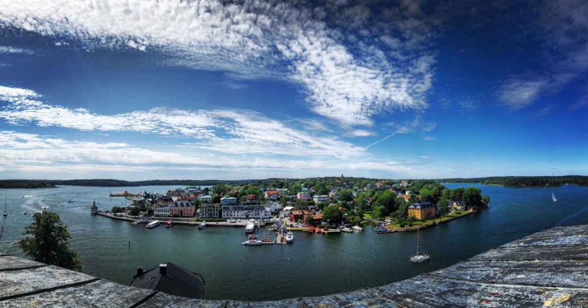 Panoramic view of Vaxholm harbor and the Stockholm archipelago, with boats, colorful houses and bright sky on a summer day trip.