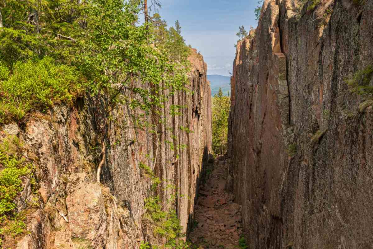 Smal bergsklyfta i Slåttdalsskrevan i Skuleskogens nationalpark, med branta klippor, stenblock och grön skog vid Sveriges Höga Kusten.