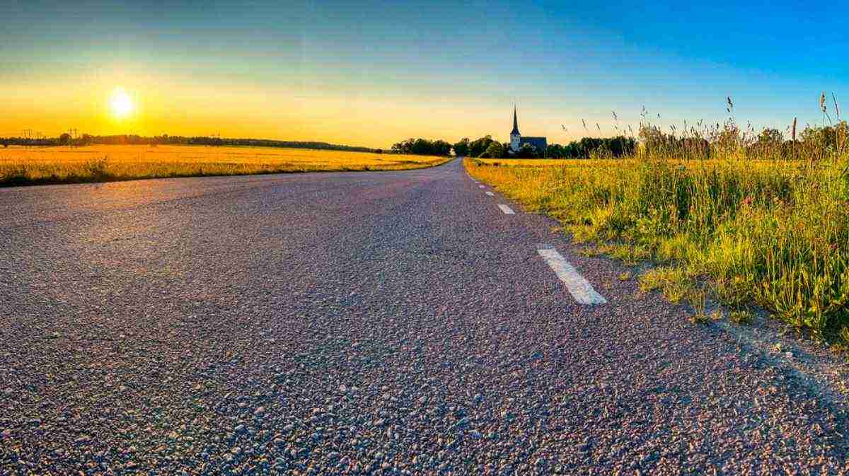 Open country road at golden hour with a church on the horizon near Västerås, a classic Swedish countryside drive from Stockholm.