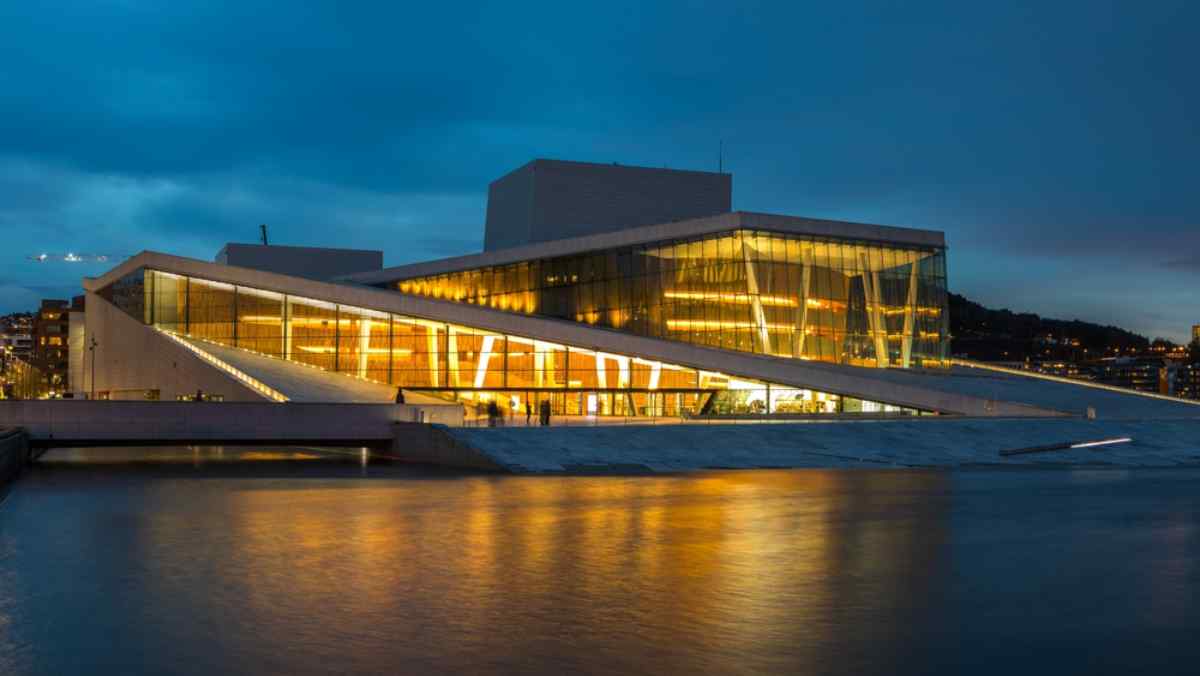 Oslos Opernhaus Das Osloer Opernhaus leuchtet in der Dämmerung, moderne Architektur spiegelt sich im ruhigen Hafenwasser.