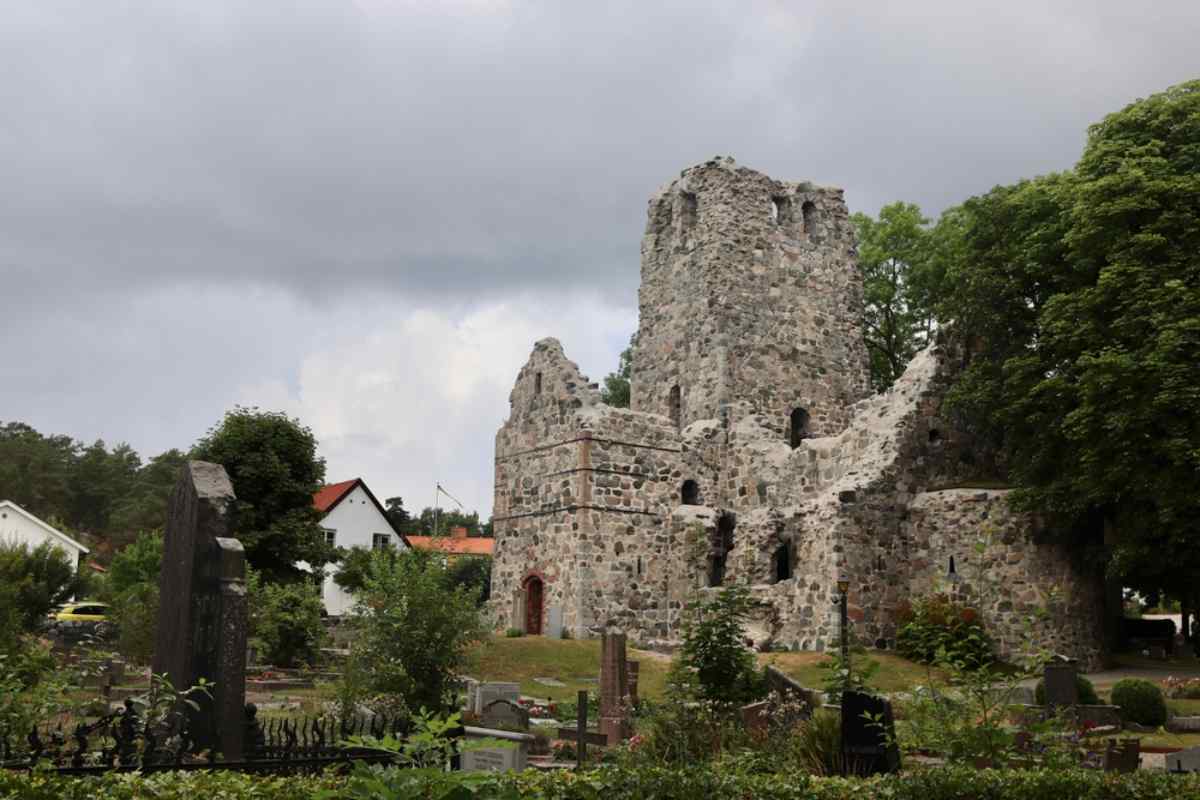 Steinerne Burgruine in Sigtuna, umgeben von Grün unter einem bewölkten Himmel.